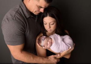 Portland Newborn Photographer parents holding baby girl swaddled in lavender