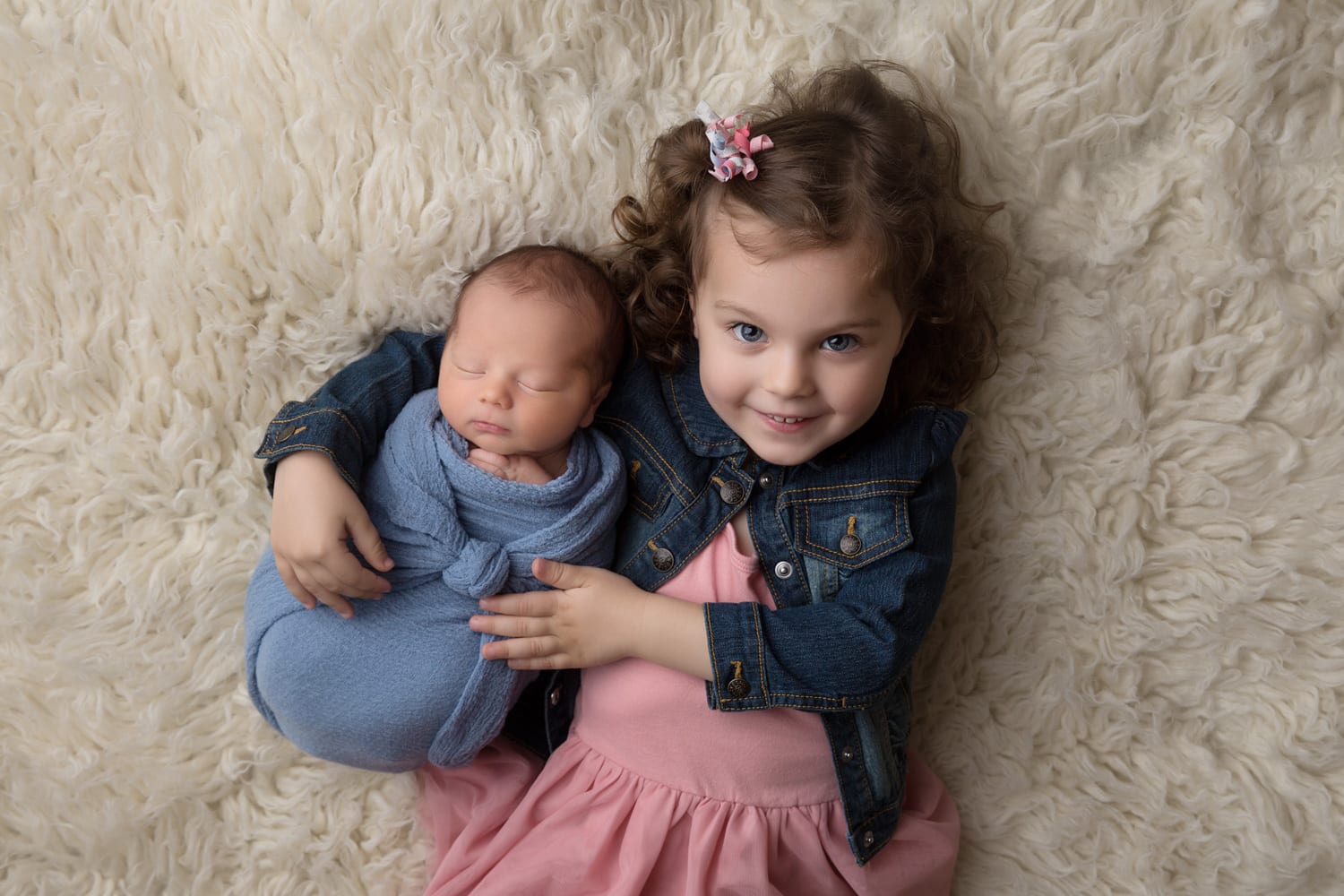 Portland Newborn Photographer big sister holding swaddled newborn brother on back