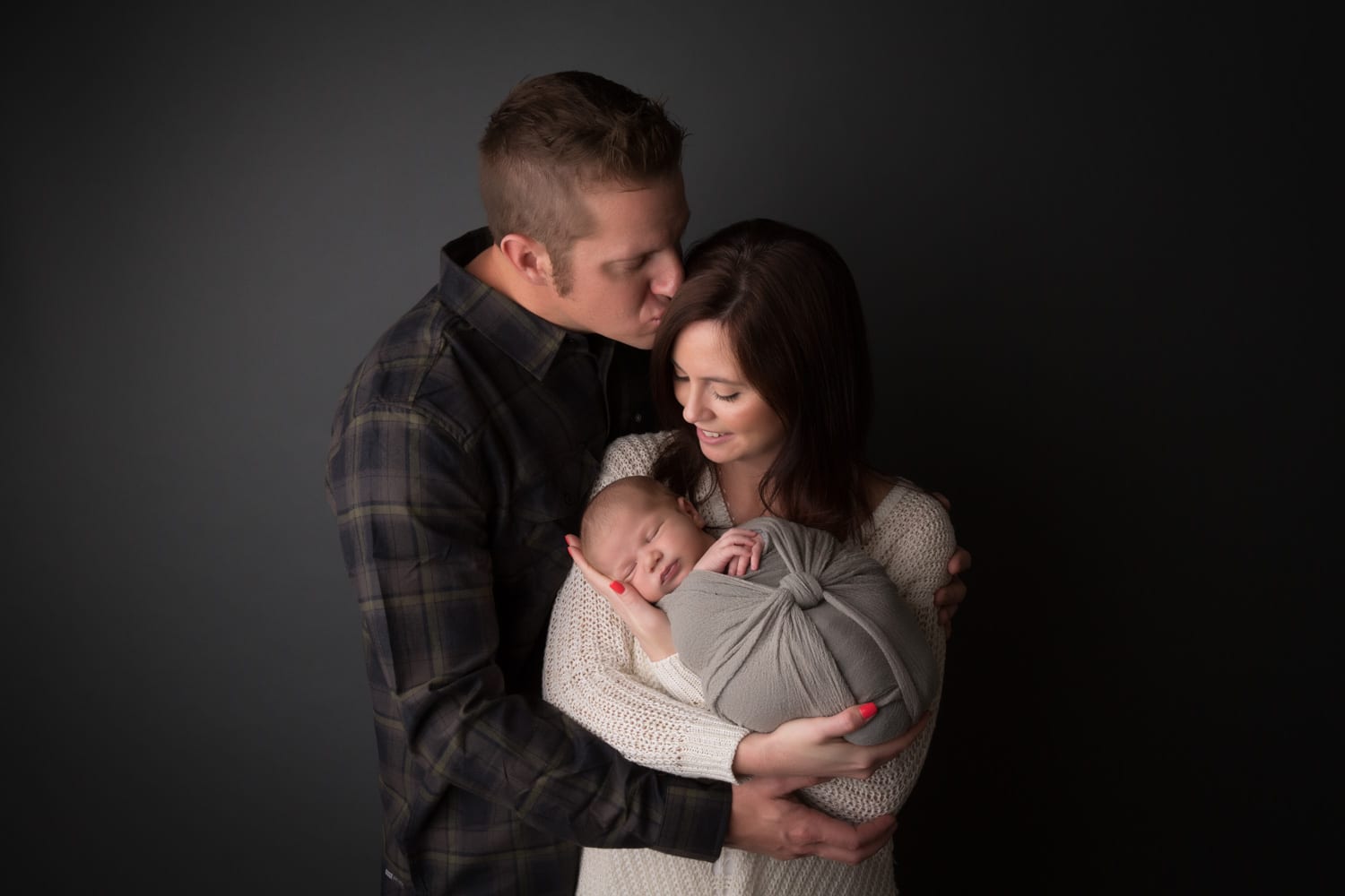 Portland Newborn Photographer mom holding baby and dad kissing mom