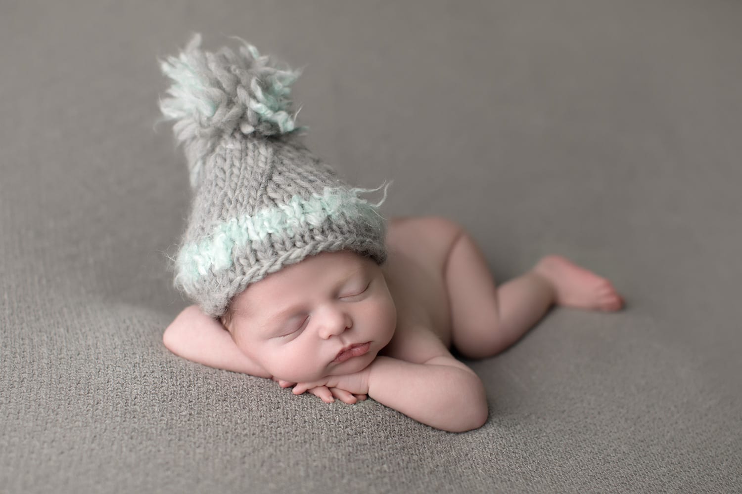 Portland Newborn Photographer newborn heads up pose wearing pom hat
