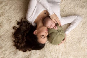 Portland Newborn Photographer mom holding baby on cream rug